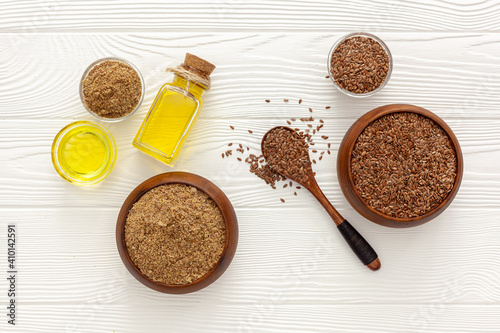 Flaxseeds in a spoon and bowl with a bottle of flaxseed oil and flaxseed flour