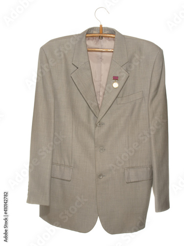 Gray jacket with a medal on a wooden hanger with a metal hook isolated on a white background.