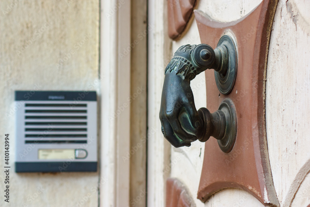 Antique door knocker contrasts with modern intercom.