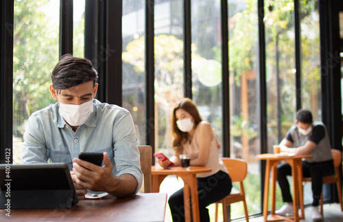 People wearing surgical masks are sitting in restaurants, coffee shops. social distancing concept Healthcare pandemic. Public safety.;