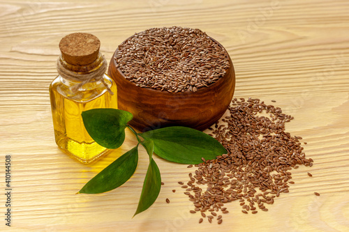 Flax seeds in a spoon and bowl with a bottle of flaxseed oil