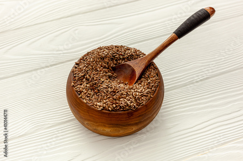 Flax seeds in a spoon and bowl with a bottle of flaxseed oil