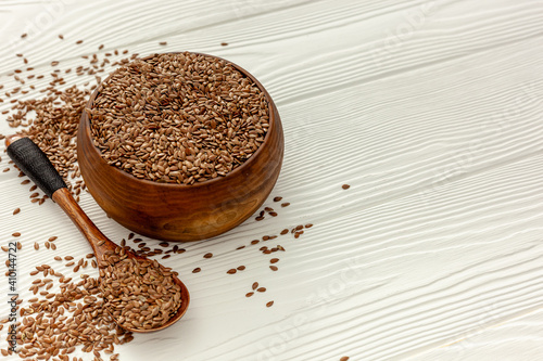 Flax seeds in a spoon and bowl with a bottle of flaxseed oil