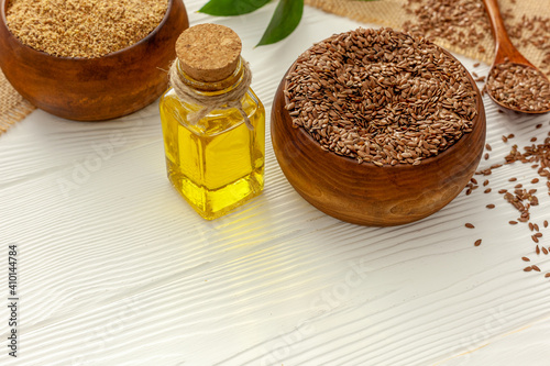 Flaxseeds in a spoon and bowl with a bottle of flaxseed oil and flaxseed flour.