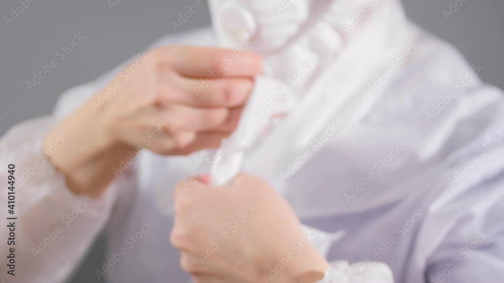 Medical worker in respirator ties hood bands on light grey Medical worker in respirator ties hood bands on light grey