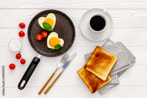 Cooking heart-shaped fried eggs in a pan