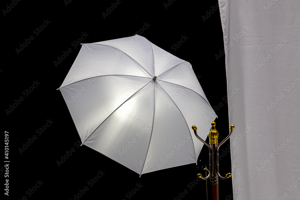 White silver reflective photo umbrella on a black background as an