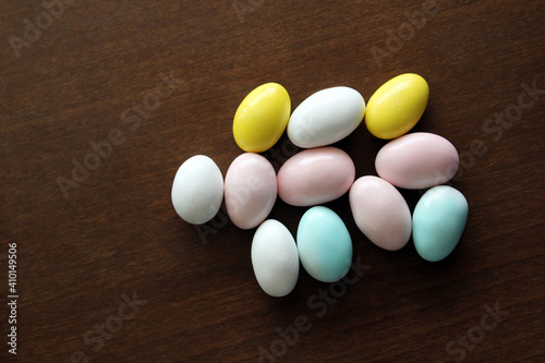 Mix of almond candies on wooden background, top view, covered chocolate candy