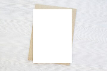 Blank vertical card mockup, invitation, greeting card mock up, brown envelope, wooden background, minimal style.