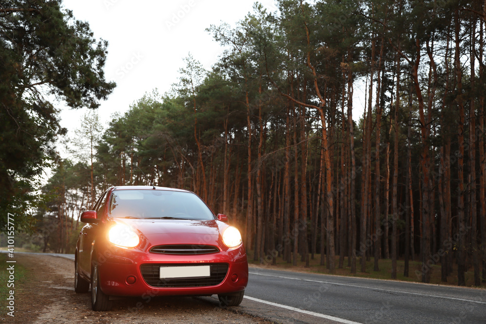 Fototapeta premium Red car parked near forest. Road trip