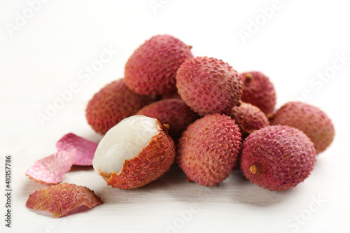 Pile of fresh ripe lychees on white wooden table, closeup
