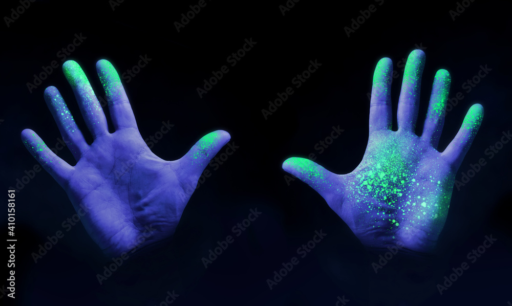 Human hands glowing from UV ultra violet light showing bacteria and
