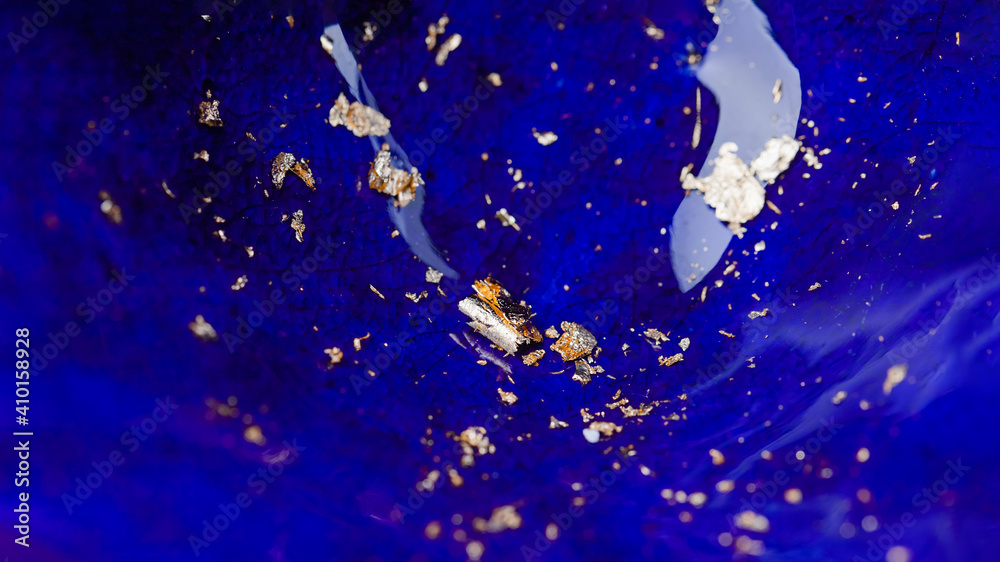 Gold foil metal flakes on deep blue ceramic enamel panorama background Gold foil metal flakes on deep blue ceramic enamel panorama background