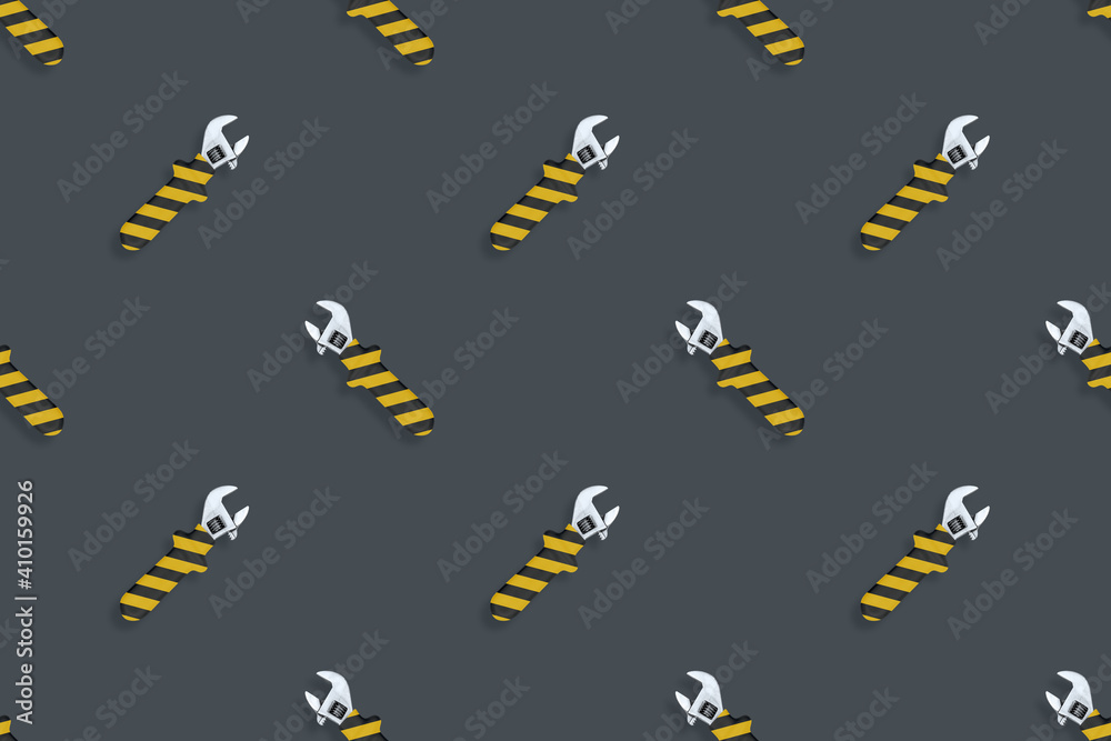 Naklejka premium Adjustable wrench seamless pattern. Background made of a metal adjustable wrench with a rubber striped handle.