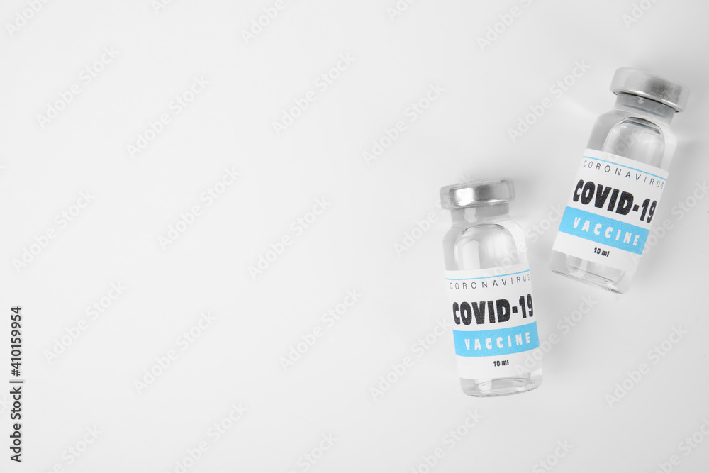 Vials with coronavirus vaccine on white background, flat lay. Space for text