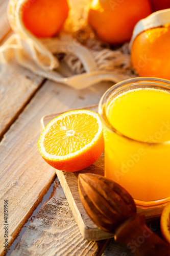 Glass of freshly sqeezed orange juice on a wooden table. Natural source of vitamins, healthy beverage for ideal breakfast. Bright sunny summer day. Close up, copy space for text. photo