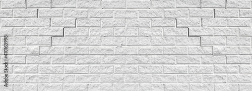 Old cracked white brick wall wide texture. Rough light gray weathered masonry background