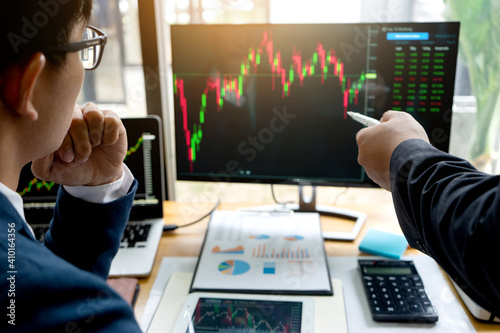 Businessmen are pointing to monitor to view stock market data on desktop