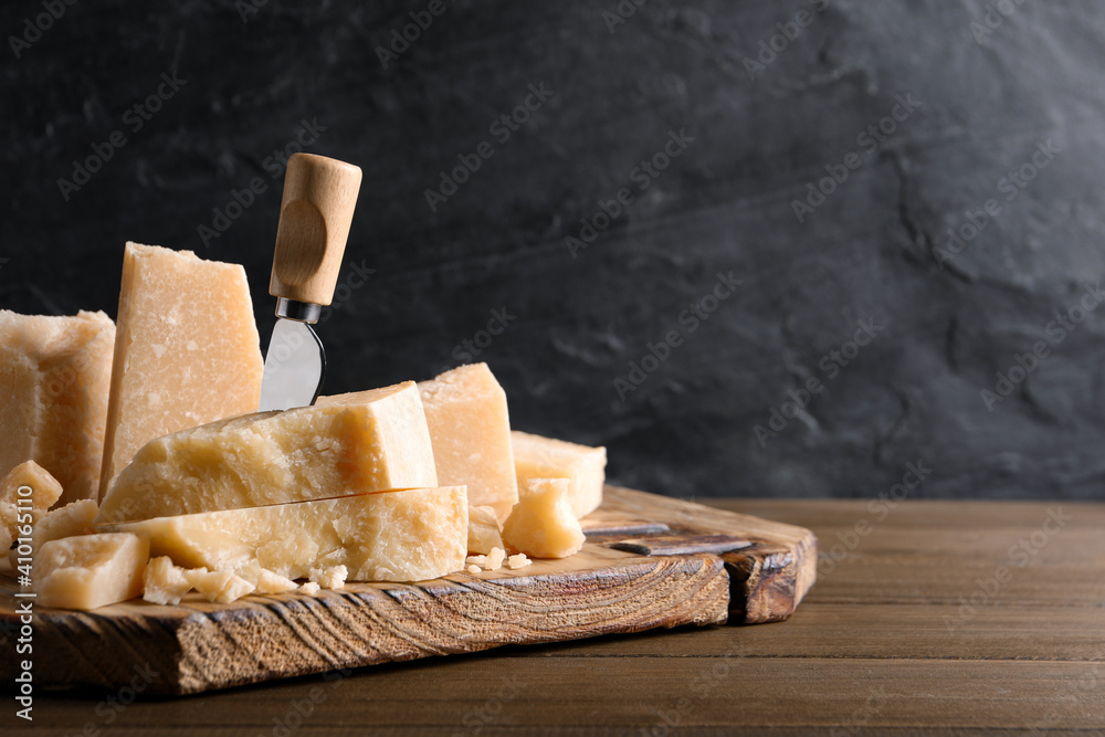 Pieces of delicious parmesan cheese with knife on wooden table. Space for text