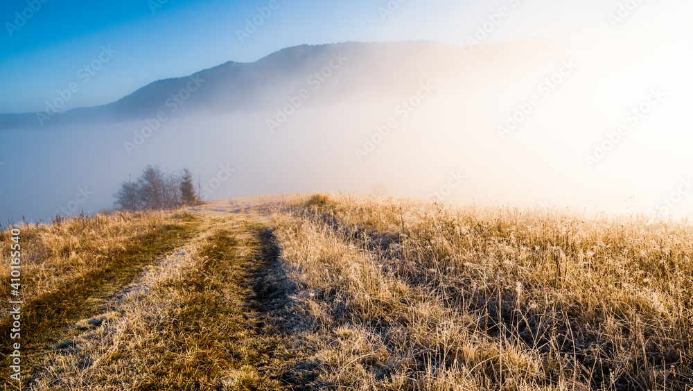 Frozen road against the backdrop of a beautiful sky and fluffy fog