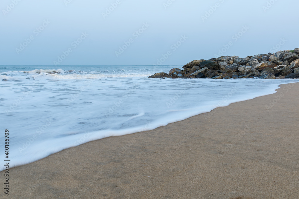 Panoramic landscape view of silky and foamy sea waves of Arabian Sea, swashing on rocky and sandy Gokarna Main Beach or Gokarna Middle Beach, Karnataka, India.