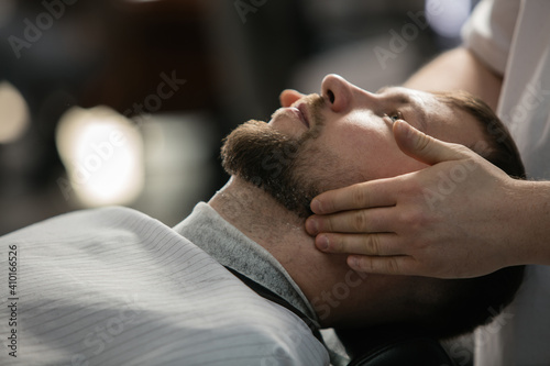 Close up of client of master barber, stylist during getting care and new look of mustache and beard. Professional occupation, male beauty and self-care concept. Soft colors and focus, vintage.