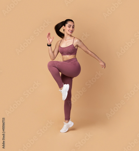 Smiling Young Woman Jumping And Exercising Isolated On Pastel Background