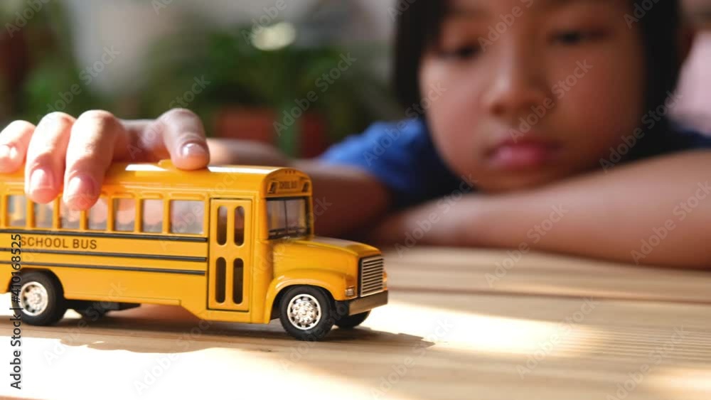 Asian child girls lonely play the yellow toy school bus during their break from school or at home. , Concept Learn at home to stop the transmission of the coronavirus or covid-19.