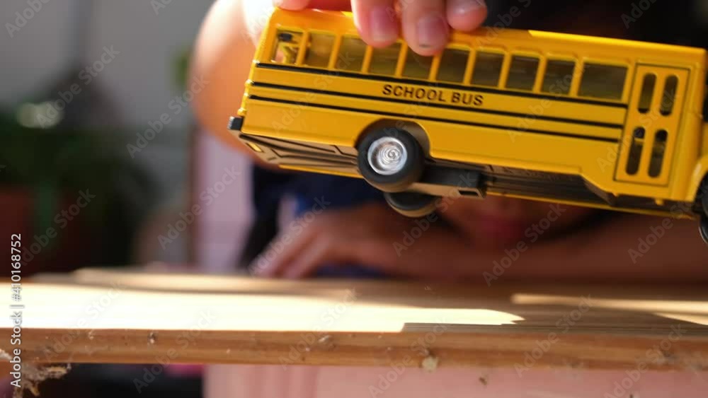 Asian child girls lonely play the yellow toy school bus during their break from school or at home. , Concept Learn at home to stop the transmission of the coronavirus or covid-19.