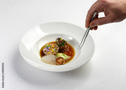 michelin star chef is decorating the conceptual cuisine plate using tweezers