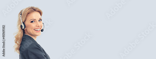 Call center. Smiling female support phone operator in headset, in grey confident suit, isolated over gray background. Customer service help consulting. Copy space blank area for some text.