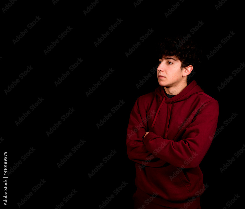 Attractive young man with curly hair posing on black studio background
