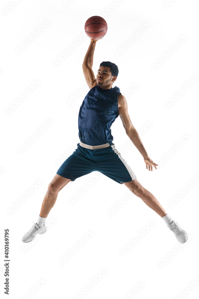 Slam dunk. Young arabian muscular basketball player in action, motion isolated on white background. Concept of sport, movement, energy and dynamic, healthy lifestyle. Training, practicing.