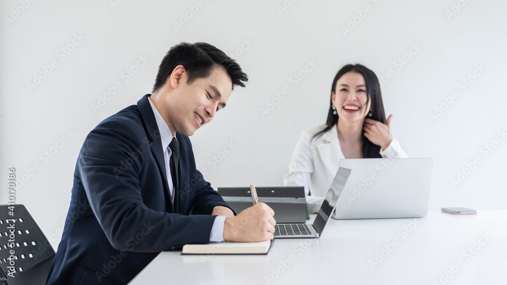 Asian businessman and businesswoman are meeting happily and using a tablet and taking notes at the office. Asian businessman and businesswoman are meeting happily and using a tablet and taking notes at the office.