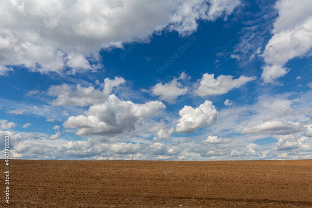 a plowed field against the sky with clouds. Spring sunny day a plowed field against the sky with clouds. Spring sunny day