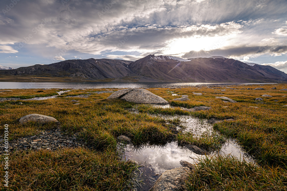 Sun reflecting in the water on a high plateau in the mountains of Kyrgyzstan