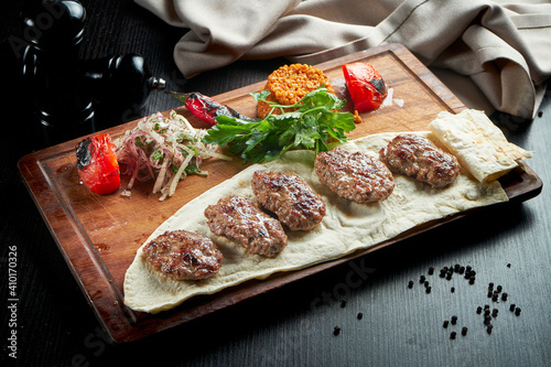 Appetizing Turkish cutlets made from lamb on a wooden board with a garnish of bulguru and grilled vegetables