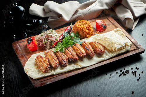 BBQ chicken wings garnished with bulgur, grilled vegetables and pickled onions. Chicken wings shashlik