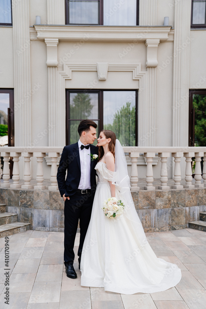 beautiful newlyweds stand against the background of a light building. beautiful newlyweds stand against the background of a light building.