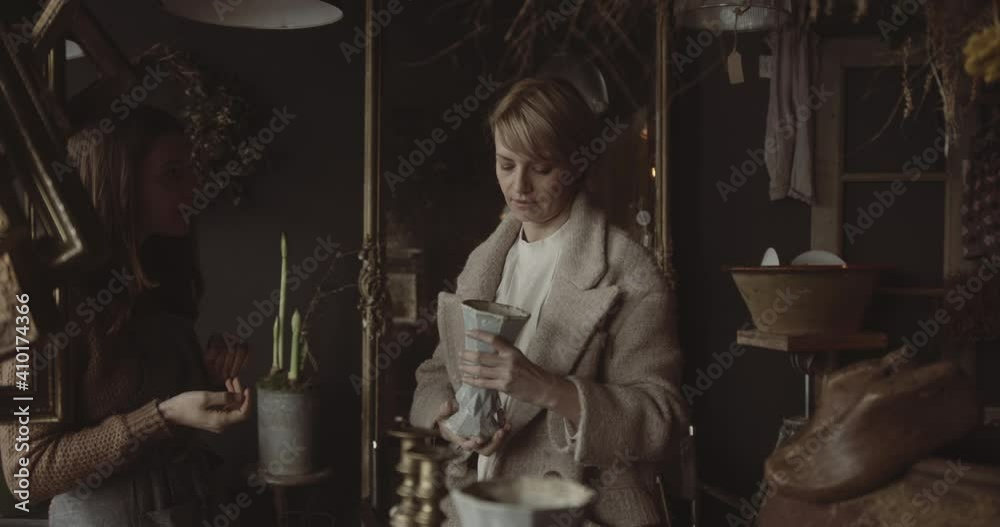 Retail shop owner advising customer in antique store on vase purchase
