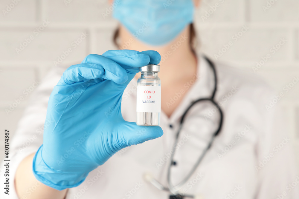 Female doctor with a stethoscope on shoulder holding syringe and COVID-19 vaccine. Healthcare And Medical concept. Female doctor with a stethoscope on shoulder holding syringe and COVID-19 vaccine. Healthcare And Medical concept.