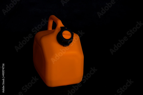 Mockup of a orange plastic canister for car fuel on a black background. Container for liquids and hazardous fuels.