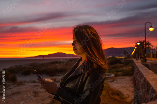 girl looking at the phone in sunset
