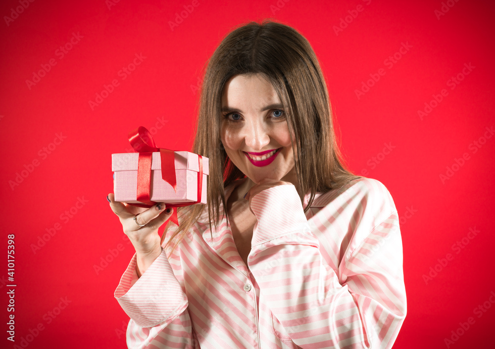 Portrait of a happy young woman holding present box isolated over red background Portrait of a happy young woman holding present box isolated over red background