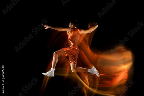 Jumping. Young arabian muscular basketball player in action, motion isolated on black background in mixed light. Concept of sport, movement, energy and dynamic, healthy lifestyle. Training, practicing