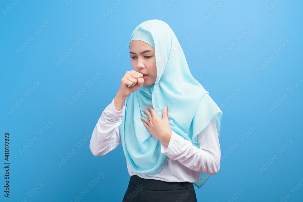 Young muslim woman with hijab feeling sick and coughing over blue background studio... Young muslim woman with hijab feeling sick and coughing over blue background studio...