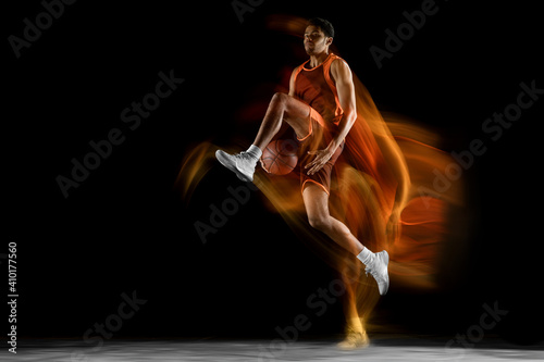 Flying. Young arabian muscular basketball player in action, motion isolated on black background in mixed light. Concept of sport, movement, energy and dynamic, healthy lifestyle. Training, practicing. © master1305