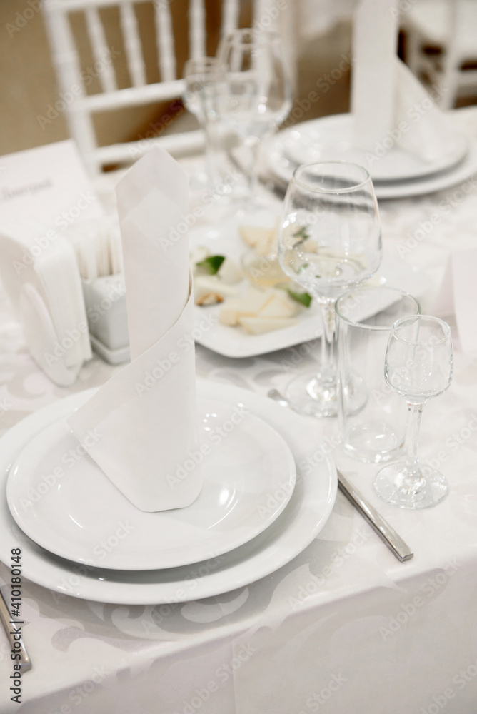 Table setting with sparkling wineglasses, plate with white napkin and cutlery on table, copy space. Place set at wedding reception. Table served for wedding banquet in restaurant