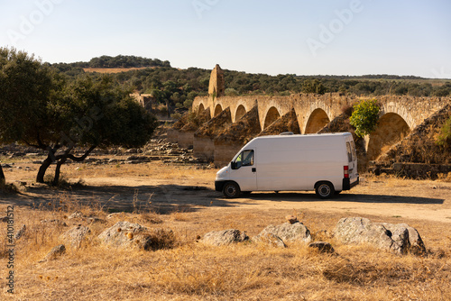 Camper van in Alentejo landscape with abandoned destroyed Ajuda bridge behind, in Portugal photo