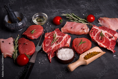 Set of various raw meat on wooden cutting board at kitchen table